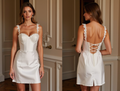 White satin mini dress with lace straps, structured cups, and lace-up back detail.