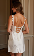 White satin mini dress with lace straps, structured cups, and lace-up back detail.