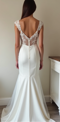 A sophisticated lace and satin mermaid wedding gown featuring a sheer illusion back with buttons, hugging the body for a timeless silhouette.
فستان زفاف راقٍ من الدانتيل والساتان، مع ظهر شفاف مزين بأزرار، يمنحك إطلالة أنيقة وفريدة.
Vestido de novia corte sirena con espalda de encaje transparente y cierre de botones, resaltando la figura con elegancia.

